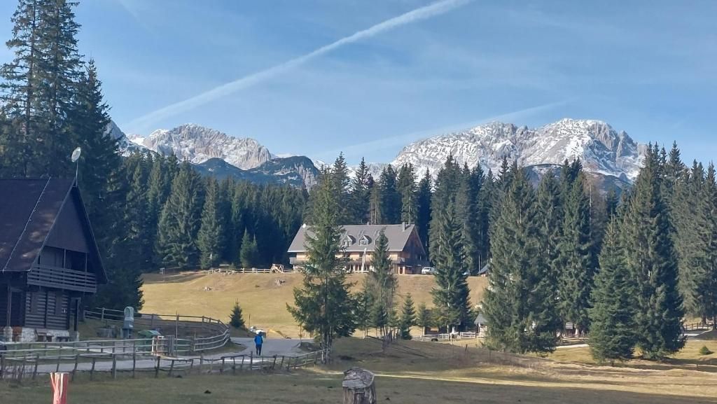 Uma hospedaria com montanhas ao fundo, uma área cercada e céu limpo.