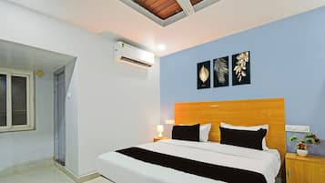 Een slaapkamer met een bed, een nachtkastje, een wandairconditioner en drie ingekaderde decoraties.