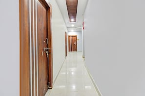 Um corredor com portas de madeira, paredes brancas e chão de azulejos.