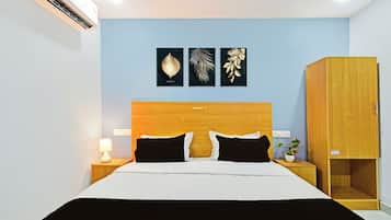Une chambre d’hôtel comprenant un lit, des tables de chevet, une lampe, une armoire et des œuvres d’art murales.