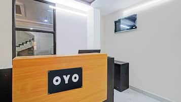 Een receptiebalie met een bordje met de tekst 'OYO' in een moderne kantooromgeving.