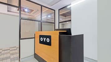 Un mostrador de recepción con un letrero que dice 'OYO' en un espacio de oficina moderno con paredes de vidrio y piso de baldosas.