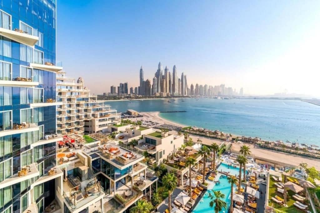 A high-rise hotel with a rooftop pool and a view of a city skyline.