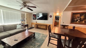 A living room with a sofa, coffee table, TV, and dining area.