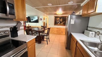 A kitchen with wooden cabinets, a stainless steel refrigerator, a microwave, and a dining area with a table and chairs.