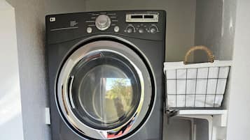 A stacked washer and dryer unit with control panels and a small shelf above.