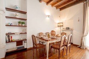 A dining area with a wooden table, chairs, and shelves with decorative items. - Elegant Stone Retreat (Bari)