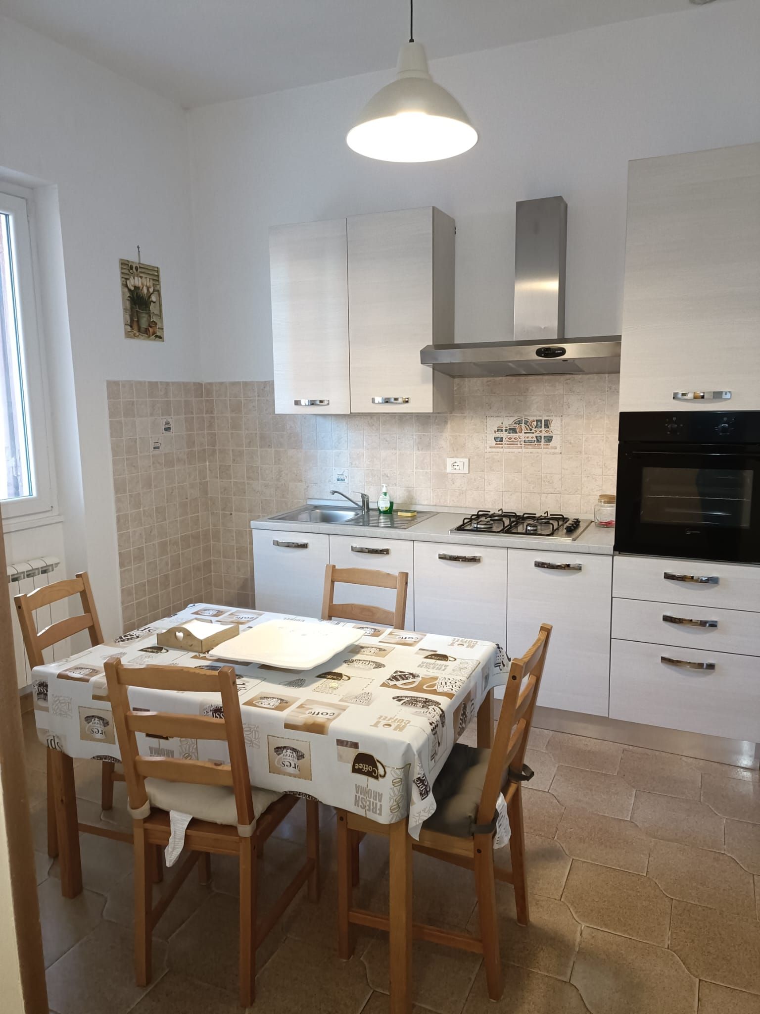 Una cucina moderna con mobili bianchi, un fornello a gas e un tavolo da pranzo per quattro persone.