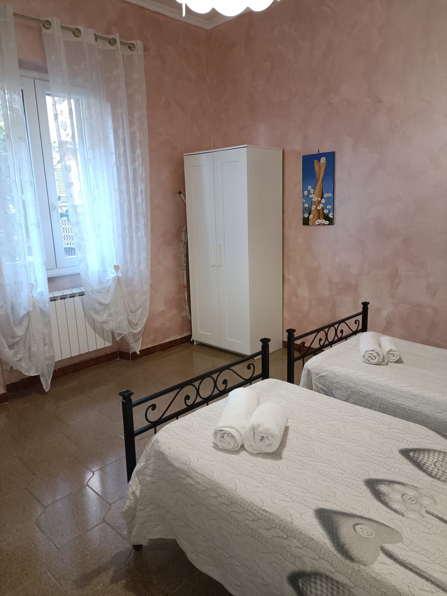 A room with two beds, a wardrobe, a radiator, and a painting on the wall.