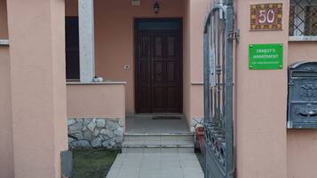L'ingresso di un edificio con un vialetto lastricato che conduce a una porta, una cassetta delle lettere e un cartello che indica 'Ernest's Apartment'.