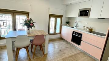 Una cocina moderna con suelo de madera, un área de comedor con dos sillas y una ventana con vistas.