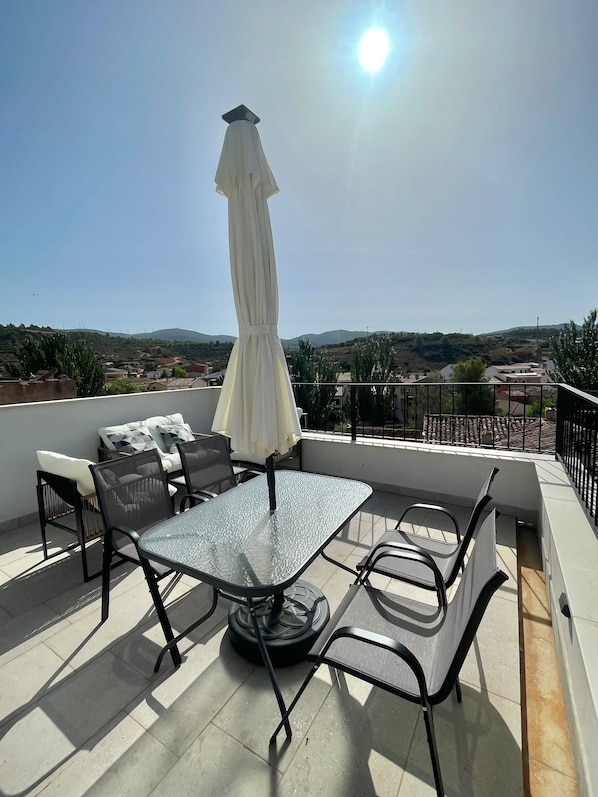 Une terrasse avec une table et des chaises, un parasol et une vue sur le paysage.