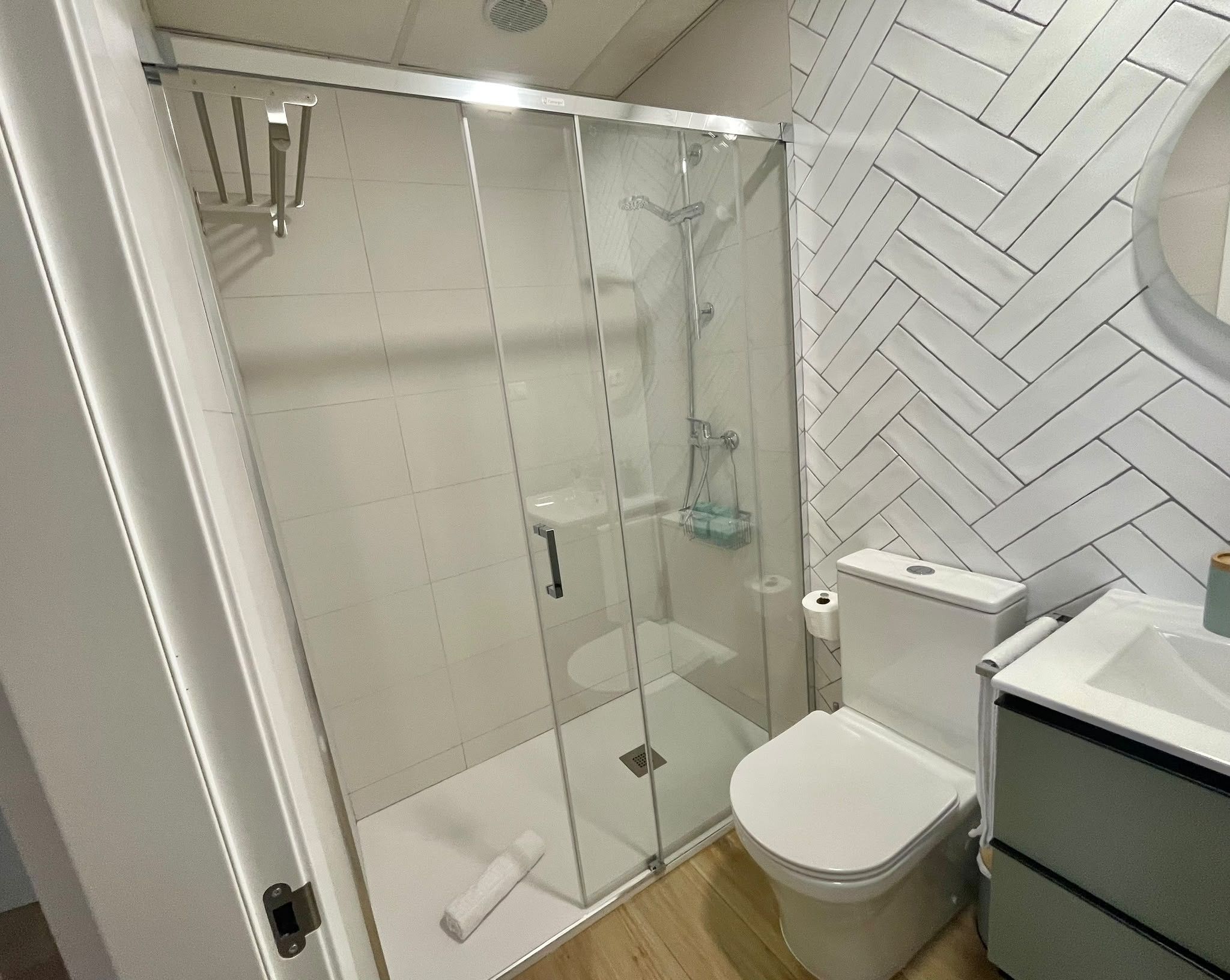 A bathroom with a glass-enclosed shower, a toilet, and a sink.