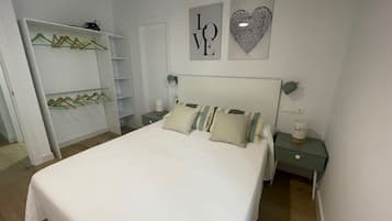 Een slaapkamer met een bed, nachtkastje, dressoir en een muur met twee prestaties.