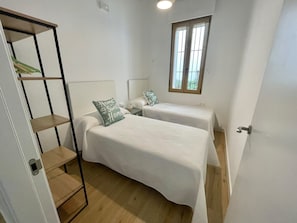 A small, single-bedroom accommodation with a bed, bedside table, and a window.