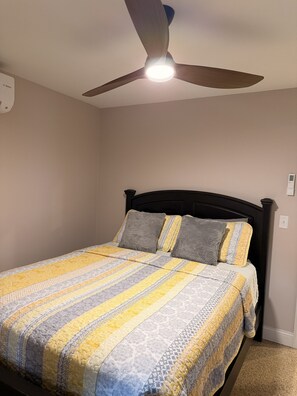 Un dormitorio con una cama, un ventilador de techo y un termostato en la pared.