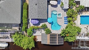 An aerial view of a property with a swimming pool, lounge chairs, and a covered area with umbrellas. - Pool Home - Close to Barefoot & Bonita Beaches (Bonita Springs)