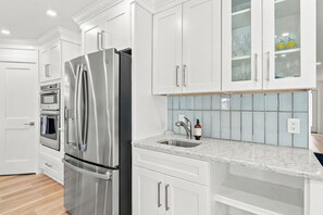 A modern kitchen with stainless steel appliances, white cabinetry, a marble countertop, and a built-in sink. - Pool Home - Close to Barefoot & Bonita Beaches (Bonita Springs)