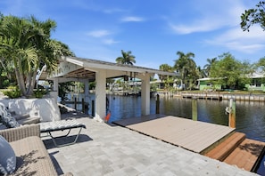 A waterfront property with a covered patio, a dock, and a lounge area with outdoor furniture. - Pool Home - Close to Barefoot & Bonita Beaches (Bonita Springs)