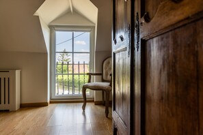 A room with a large window, a radiator, a wooden door, and a chair. - Spacious, charming cottage 'Les Glycines' with Shared Pool, Private Garden and Wi-Fi (Monteaux)