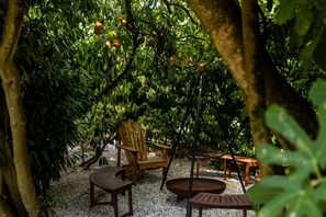 A secluded outdoor seating area with wooden furniture and hanging light fixtures amidst dense foliage. - Spacious, charming cottage 'Les Glycines' with Shared Pool, Private Garden and Wi-Fi (Monteaux)