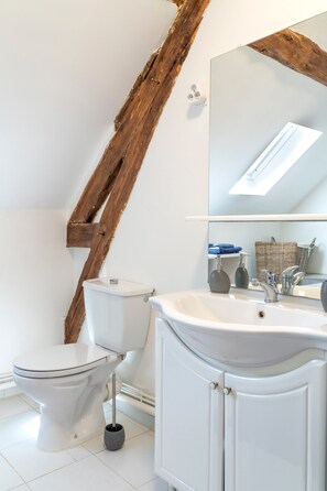 Ein modernes Badezimmer mit Toilette, Waschbecken und Spiegel.