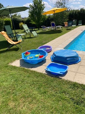 A backyard with a swimming pool, lounge chairs, and inflatable pools. - 'Les Hortensias', country-style cottage with Shared Pool, Private Terrace and Unlimited Wi-Fi (Monteaux)