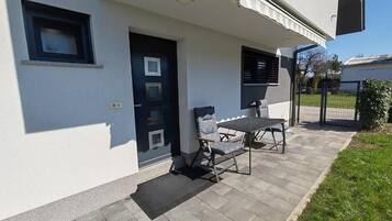 Un edificio con puerta, ventana y un patio con mesa y sillas.