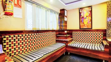 A hotel room with a sofa set, a fire extinguisher, and a wall-mounted certificate.