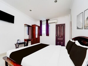 Ein Hotelzimmer mit einem Bett, einem Schreibtisch, einem Kleiderschrank und einem an der Wand befestigten Fernseher.