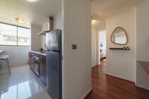 A modern kitchen with stainless steel appliances, a wooden floor, and a view to the living area. - Your Serene Getaway Central Providencia (Providencia)