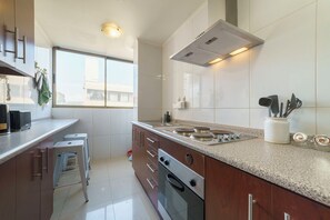 Una cucina moderna con piano cottura a gas, forno ed elettrodomestici in acciaio inossidabile. Una finestra offre luce naturale e vista all'esterno.