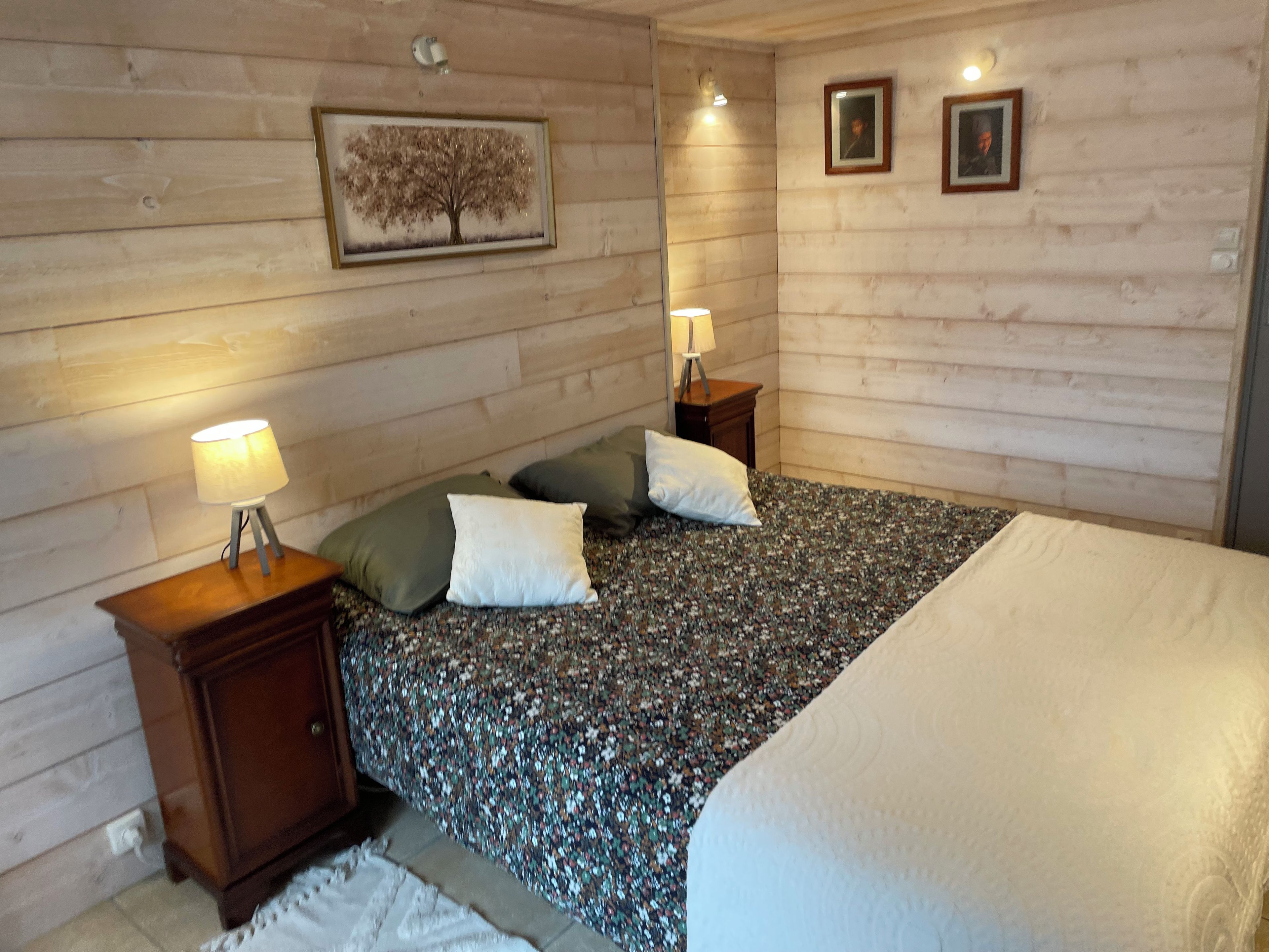 Een slaapkamer met een bed, twee nachtkastjes, een lamp en een lijst aan de muur.