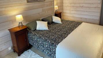 Een slaapkamer met een bed, twee nachtkastjes, een lamp en een lijst aan de muur.