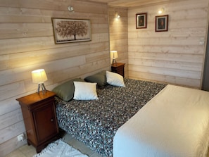 A bedroom with a bed, two nightstands, a lamp, and a framed picture on the wall.