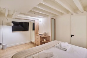 A bedroom with a bed, a bedside table, a mirror, a wardrobe, and a TV on the wall. - Air-Conditioned Loft - Bastille Le Marais (Paris)