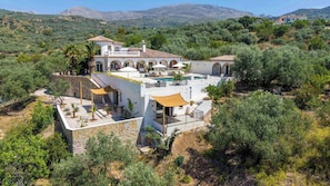 Eine mediterrane Villa mit Pool, Sitzgelegenheiten im Freien und Blick auf die umliegenden Hügel.