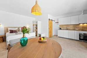 Eine moderne Küche mit weißen Schränken, einer Holztür und einem Essbereich mit einem runden Tisch und einem Blumenstrauß.