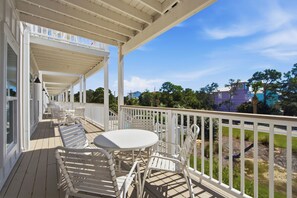 A covered outdoor area with white furniture and a view of a swimming pool and buildings in the background. - Gulf View, Great Location, Pool, Hot Tub, Tennis (Santa Rosa Beach)