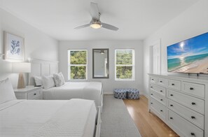 A bedroom with two beds, a ceiling fan, a large window with blinds, a dresser, and a painting of a beach. - Gulf View, Great Location, Pool, Hot Tub, Tennis (Santa Rosa Beach)