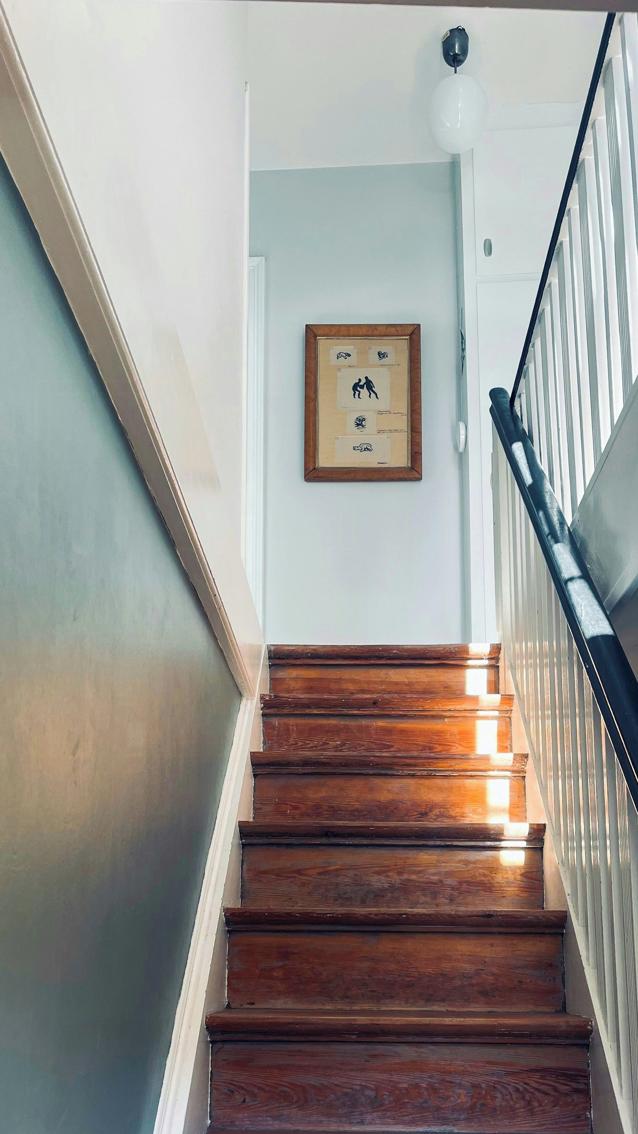 Una escalera de madera con un cuadro enmarcado en la pared superior.