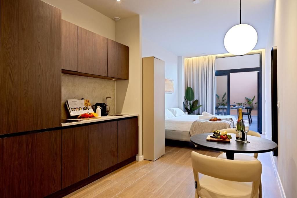 Una cocina moderna con armarios de madera, un comedor con mesa y sillas, y vista a un balcón con plantas.