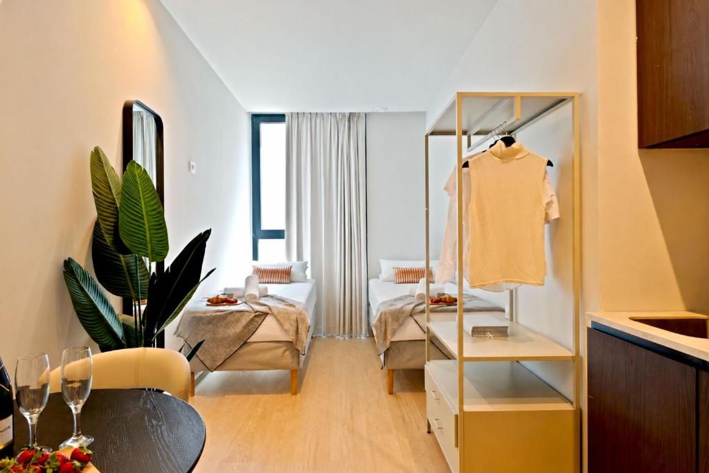 Habitación de hotel compacta con dos camas, una pequeña mesa de comedor, un espejo y un armario.
