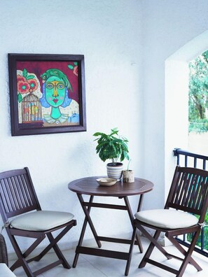 A small balcony with a round table and two chairs, a framed painting, and a potted plant. - 2 BDR Amazing Beachfront Condo (Cancún)