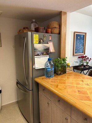 A kitchen with a refrigerator, a wooden countertop, a water bottle, and a calendar. - 2 BDR Amazing Beachfront Condo (Cancún)