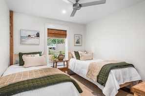 A bedroom with two beds, a ceiling fan, and a window with a view. - Coastal Vista (Santa Rosa Beach)
