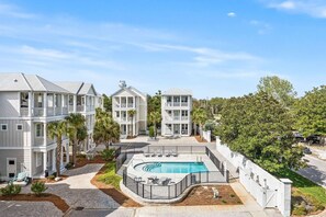 A multi-story residential building with a swimming pool, surrounded by palm trees and a well-maintained lawn. - Serenity by the Sea 30A (Panama City Beach)