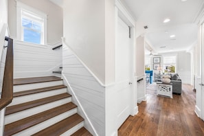 A staircase with wooden steps leading to a room with a gray couch and a coffee table. - Serenity by the Sea 30A (Panama City Beach)