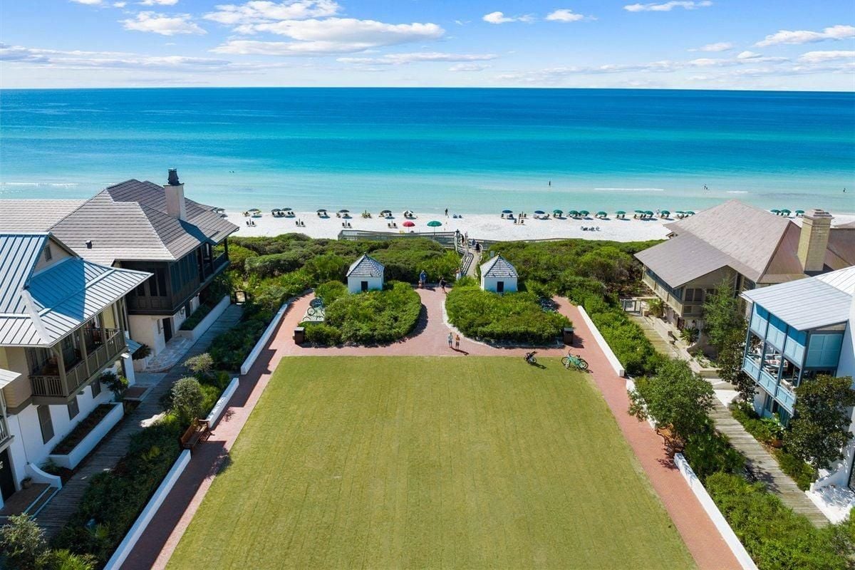 A coastal property with a large lawn, beach access, and multiple buildings.