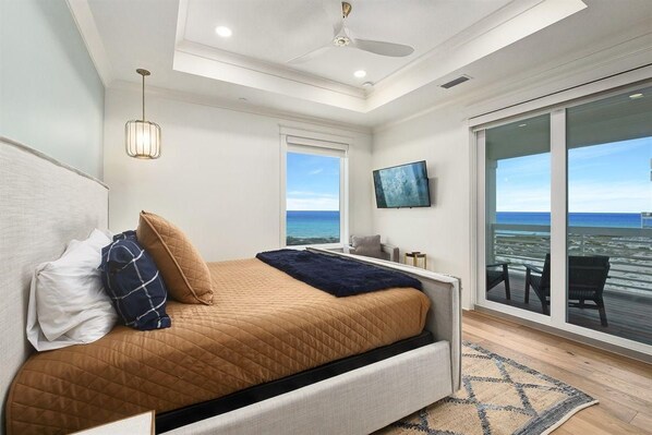 A bedroom with a bed, a ceiling fan, a TV, and a view of the ocean. - Amberjack (Panama City Beach)